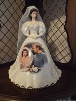 Front view of porcelain figurine showing character, printed scene, gold trim, veil