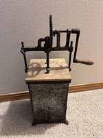 Full view of churn showing metal body, gear mechanism, wooden handle, top lid