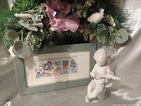 Figurine front view beside framed cross-stitch