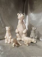 Group view of five polar bear figurines showing sizes and poses
