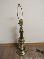 Full view of brass lamp base with harp, finial and cord