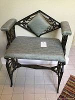 Full view of chair showing wrought iron frame, mint green padded armrests, seat, and diamond-shaped back cushion.