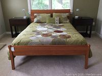 Full front view of assembled bed with green bedding, flanked by nightstands