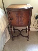 Front view showing the tiger maple top, small storage door, curved legs, and stretcher base.