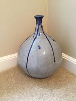 Full front-side view of the large pottery vase placed on carpeted floor near wall, showing shape and glaze drip design