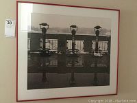 Full view of framed black and white photo showing three binocular viewers at Niagara Falls with reflections and snow, in red frame.