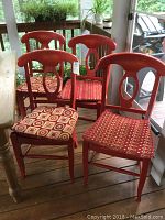 Four red wood Eleanor Napoleon style side chairs with rush woven seats and reversible patterned cushions on a wooden floor.