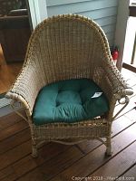 Front view of wicker armchair with dark green cushion on porch
