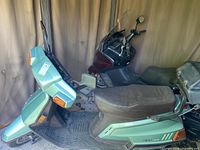 Full left side view of green Yamaha Riva XC125 scooter with cargo box, windshield and seat