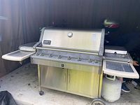 Full view of Weber Summit Platinum grill with propane tank and side shelves unfolded