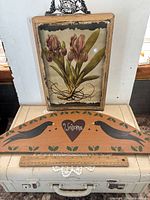 Shadowbox print standing atop suitcase with wooden Welcome sign beneath