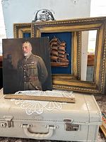 Overall lot: framed ship relief, empty ornate frame, portrait board, doily on suitcase