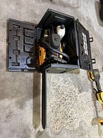 Chainsaw inside open hard case with oil bottle