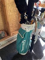 Full view of teal Spalding bag with clubs and umbrella