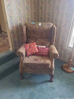 Front view of wingback recliner with two throw pillows on seat