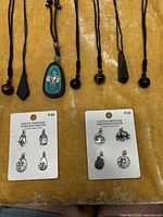 Overview of five cord necklaces with various pendants and two Positive Intentions charm cards