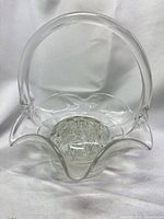Front view of clear glass basket with flower frog seated inside