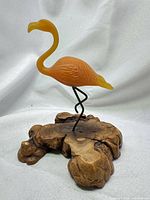 Full view of flamingo sculpture showing color, pose and burl wood base