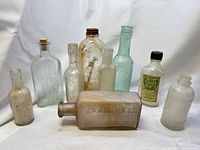 Group view showing nine antique glass bottles in various sizes, colors and positions