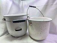 front view of both white enamel buckets showing size difference, handles, and trim