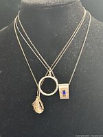 All three necklaces shown for scale; lot is the silver-tone circle pendant on longest chain
