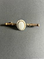 Front view of brass bar brooch showing cabochon and pearl halo