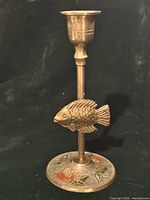 Full view of brass candlestick showing fish figure and holder cup