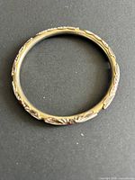 Top view of entire bracelet showing floral enamel pattern and gold tone