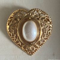 Front view showing pearl/cream cabochon side within heart filigree frame