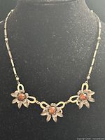 Full view of necklace showing three floral stations and chain style