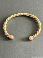 Full view of twisted multi-tone cuff bracelet with ball ends