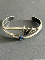 Full view of silver-tone open cuff bracelet showing overall style and cabochon placement