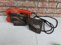 Left side view showing Black & Decker belt sander with dust bag and cord