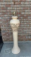 Full view of ceramic floor lamp against brick wall