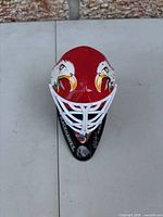 Front top view of red mini goalie helmet with eagle graphics on black Blackhawks stand
