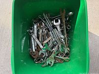 Top view of green bin filled with assorted combination wrenches