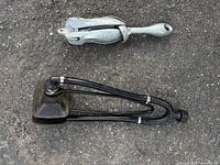 Anchor folded beside bilge pump hose assembly on asphalt