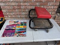 Overall view of mechanic creeper seat with four magazines on table