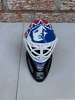 Front view of miniature goalie mask on stand