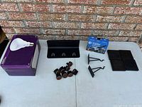 All lot contents on table: bulb box with sample bulb, wall rail with hooks, bracket arms, vacuum box, rubber pads, felt sliders