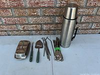 Thermos, butter dish, pie server, carving knife, bundle of flatware and metal straws displayed together