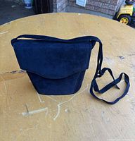 Front view of navy suede crossbody bag showing flap and strap