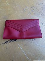 Front view of red leather bag showing V-shaped stitched flap detail