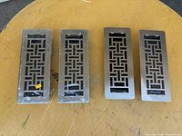 Four stainless steel floor registers showing brushed fascia pattern; two still shrink-wrapped