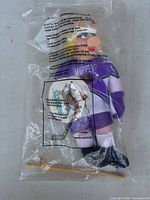 Front view of sealed Miss Piggy plush showing hockey uniform and accessories inside bag