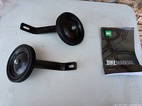 pair of black training wheels with steel brackets and MEC bike manual