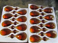 Two trays holding 17 amber teardrop chandelier crystals with octagon connectors