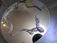Full view of rhinestone necklace on mirror showing pear-cut center and chain