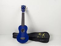 Front view of blue Strong Wind soprano ukulele beside black gig bag