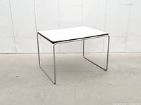 three-quarter view showing white laminate top, black edge banding, chrome sled base
